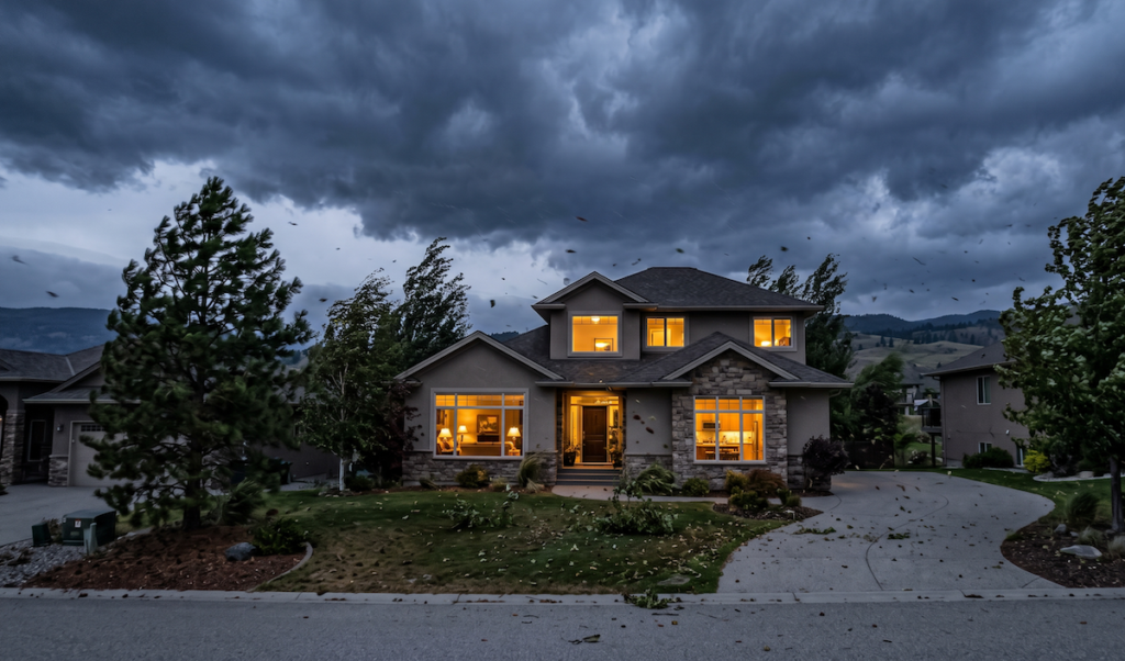 4b2 - Kemp Co Electric Two-story suburban house at dusk with warm indoor lights, curved driveway, and windy, stormy sky.